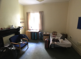 Bedroom with a single bed, a desk with drawers, and an armchair.