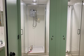Two shower cubiles with a sink and mirror next to them.