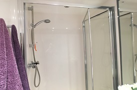 A shower cubicle with two towels hung up next to it.
