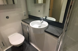 A bathroom with a toilet, sink and mirror.