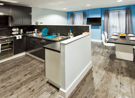 Shared kitchen and communal area, showing a cooker and hob, sink, and kitchen storage units. Nearby is a dining table with four chairs