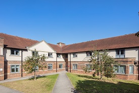 Exterior of a large two-storey red brick building, with two trees in front of it.