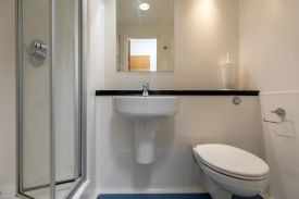 A bathroom with a toilet, sink, mirror and shower cubicle.