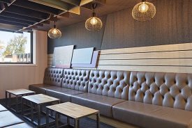 A room with seats lined along two opposite walls, and a series of samll tables in the middle.