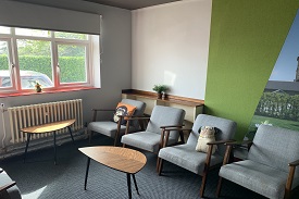 A room with five armchairs arranged around two coffee tables.