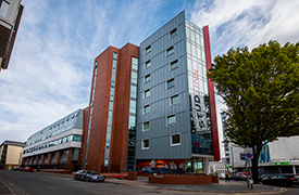Exterior of a modern eight-storey building on the corner of two roads.