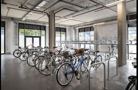 A bike storage unit with large windows and bike racks holding multiple bikes