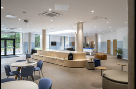 the common room in Metal Works.The are a a couple of small circular tables visible, as well as soft seating with small circular side tables attached. In the centre of the room is a long island bench. In the background is a snooker table. 