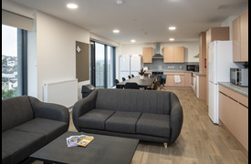 A kitchen and dining room with worktops, cupboards, dining table and chairs, sofas and coffee table